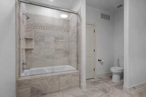 Bathroom featuring tiled shower / bath and toilet