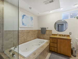 Bathroom with vanity, a whirlpool tub, tile walls, tiled shower, and recessed lighting