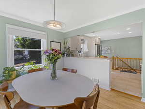 Dining space featuring light wood-style floors, crown molding, and recessed lighting