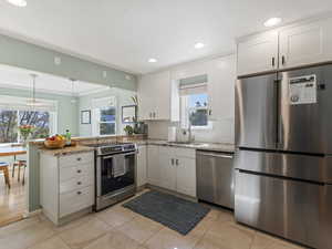 Kitchen with stainless steel appliances, white cabinetry, recessed lighting, decorative backsplash, and a peninsula