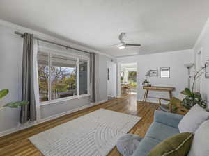 Living room featuring light wood finished floors, crown molding, and ceiling fan