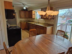 Kitchen with ornamental molding, dark stone countertops, tasteful backsplash, black appliances, and light wood-style floors