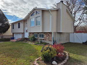 Split foyer home featuring brick siding, a chimney, and a gate