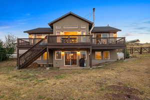 Rear view of house featuring a wooden deck, stucco siding, stairs, and oil tank