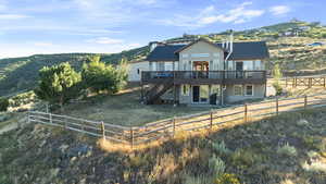 Back of property with stairs, a deck with mountain view, a fenced backyard, and stucco siding