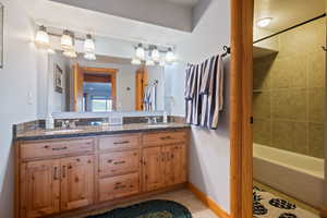 Full bathroom with double vanity, light tile patterned floors, and shower combination