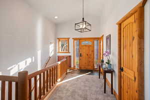 Carpeted foyer entrance featuring high vaulted ceiling and a chandelier