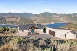 View of front facade with an outdoor structure, a patio area, driveway, and a water and mountain view