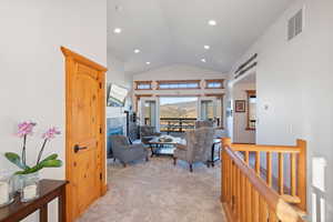Living area featuring light carpet, a tiled fireplace, high vaulted ceiling, and recessed lighting