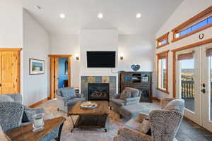 Living area with high vaulted ceiling, recessed lighting, french doors, a tile fireplace, and stone finish floors