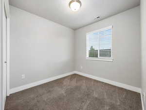 Unfurnished room featuring carpet and a textured ceiling