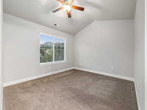 Carpeted empty room with lofted ceiling and ceiling fan