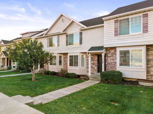 View of front facade featuring a front lawn, stucco siding, and roof with shingles