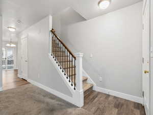 Stairs featuring a textured ceiling, a chandelier, and wood finished floors