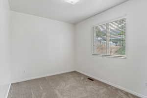 Carpeted spare room featuring baseboards