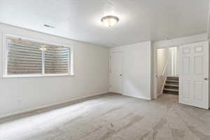 Unfurnished bedroom with light carpet and a textured ceiling