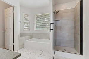 Full bathroom with a shower stall, a garden tub, marble look tiles, and vanity