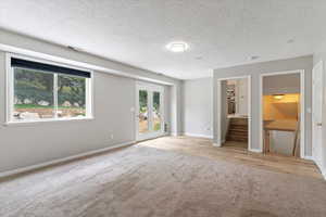 Unfurnished room with light carpet, a textured ceiling, and stairs