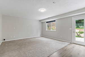 Empty room with a textured ceiling and light wood finished floors