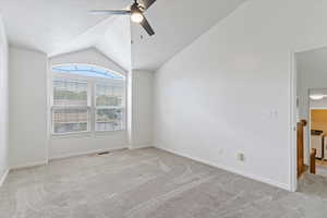 Unfurnished room with light colored carpet, vaulted ceiling, ceiling fan, and washer / clothes dryer