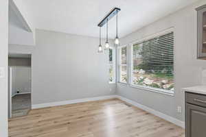 Unfurnished dining area featuring light wood finished floors and baseboards