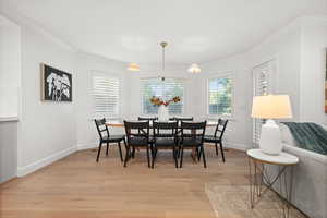 Dining area with ornamental molding and light wood-style flooring