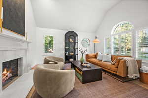 Living area featuring high vaulted ceiling, wood finished floors, and a high end fireplace