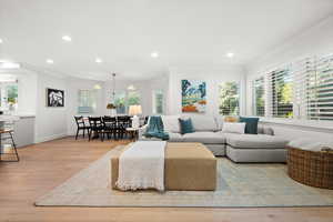 Living room with light wood finished floors, crown molding, and recessed lighting