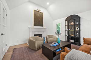 Living area with vaulted ceiling, a fireplace, wood finished floors, and recessed lighting