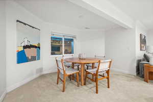 Dining space with crown molding and light carpet