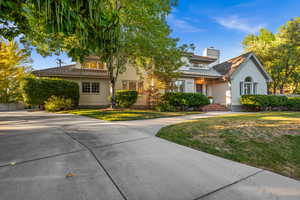 View of front of property featuring a chimney, a front lawn, brick siding, and concrete driveway