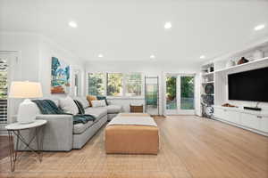 Living room featuring recessed lighting, ornamental molding, healthy amount of natural light, and light wood finished floors