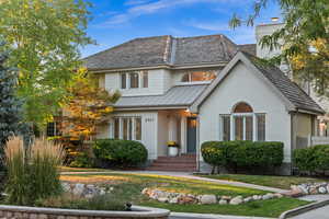 View of front of home with brick siding, a front yard, a standing seam roof, and a metal roof