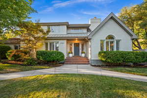View of front of home featuring brick siding, a standing seam roof, a front yard, and a chimney