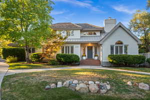 View of front of property with a standing seam roof, brick siding, a chimney, a metal roof, and a front yard