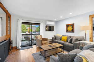 Living area with light wood-type flooring, recessed lighting, and a wall mounted AC