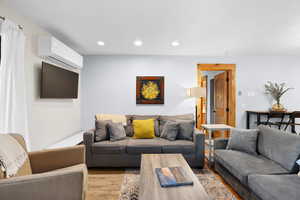 Living area featuring wood finished floors, recessed lighting, and a wall unit AC