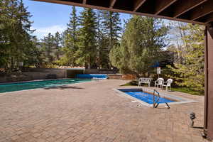 View of pool with a covered pool, a fenced backyard, a patio area, and an in-ground hot tub