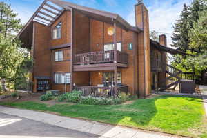 Back of property featuring a chimney, a lawn, and a wooden deck