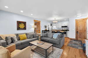 Living room with light wood-type flooring, recessed lighting, and a chandelier