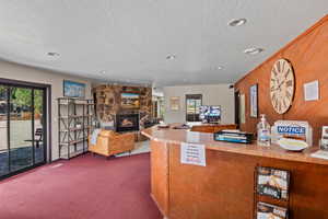 Kitchen with a textured ceiling, dark carpet, light countertops, a stone fireplace, and wooden walls