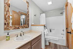Bathroom featuring shower / tub combo, vanity, and dark wood-style flooring