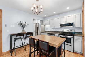 Kitchen featuring stainless steel appliances, light wood-style flooring, pendant lighting, a chandelier, and recessed lighting