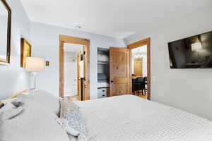 Bedroom with a chandelier, connected bathroom, and wood finished floors