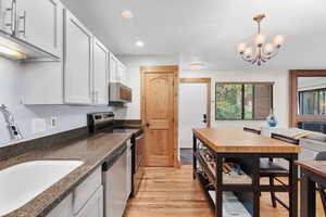 Kitchen with appliances with stainless steel finishes, light wood-type flooring, hanging light fixtures, recessed lighting, and a chandelier