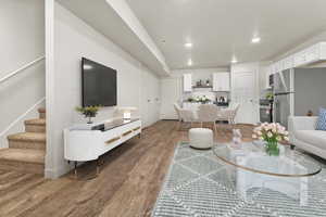 Living room with stairs, light wood finished floors, and recessed lighting
