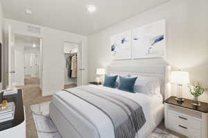 Bedroom featuring light colored carpet and a walk in closet
