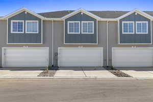 View of front facade with board and batten siding, roof with shingles, and a garage