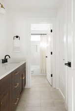 Bathroom with shower / bathtub combination with curtain, vanity, and light tile patterned flooring