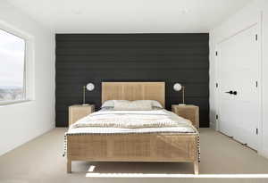 Bedroom featuring carpet floors, wood walls, and a closet